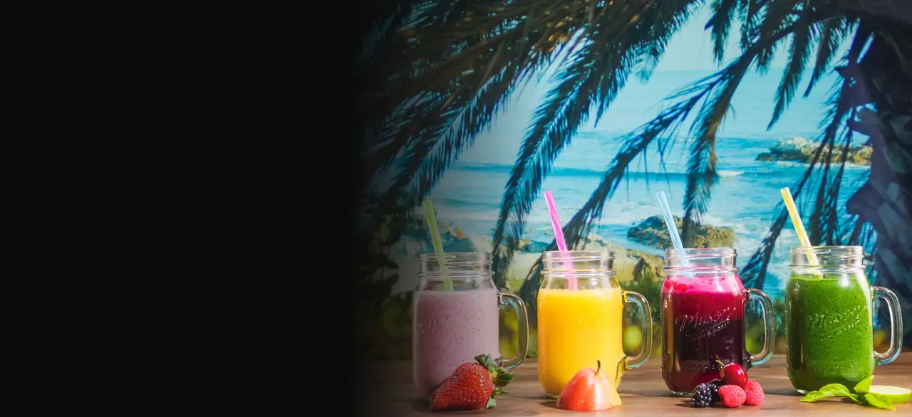 Quatro potes de vitamina coloridos sobre o balcão, com o mar ao fundo