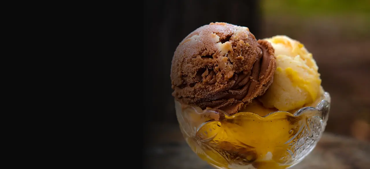 Duas bolas de sorvete de chocolate e baunilha numa taça de vidro